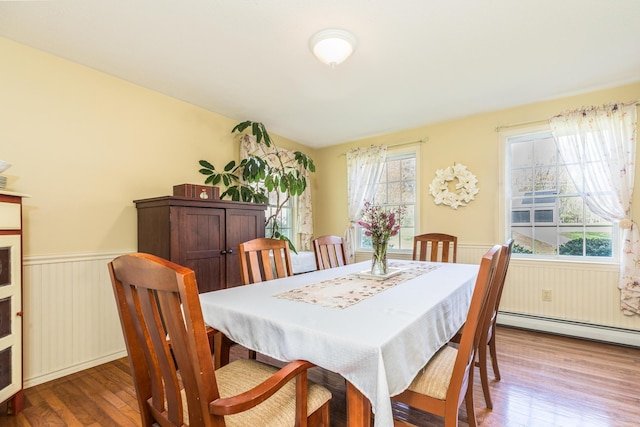 dining room featuring wood finished floors, a baseboard radiator, and a wainscoted wall