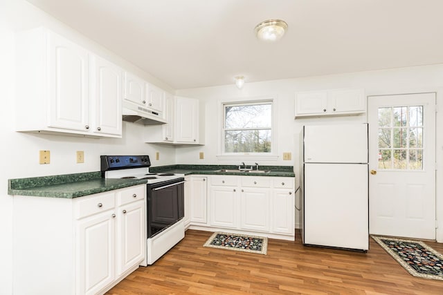 kitchen with dark countertops, electric stove, freestanding refrigerator, a wealth of natural light, and under cabinet range hood