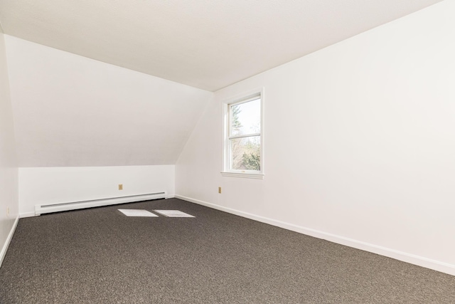 additional living space featuring baseboards, a baseboard radiator, dark carpet, and lofted ceiling