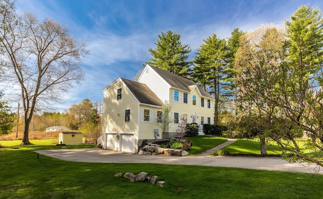 view of property exterior featuring a garage, a storage shed, a lawn, an outdoor structure, and driveway