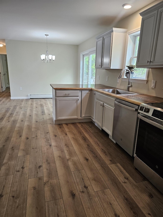 310 Emery Mills Rd, Shapleigh, ME 04076 - kitchen with a baseboard heating unit, stainless steel appliances, a sink, a peninsula, and a chandelier