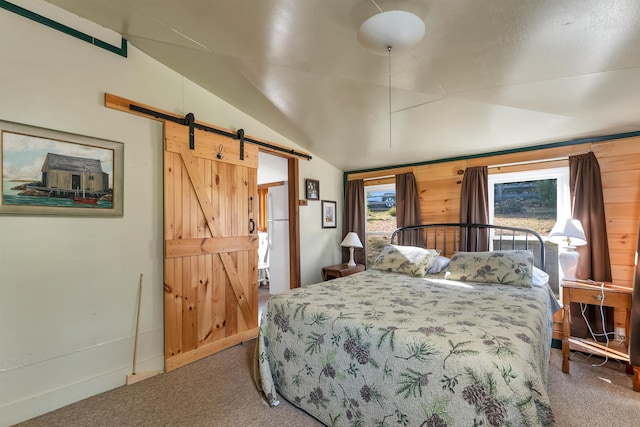 bedroom featuring carpet, vaulted ceiling, and a barn door