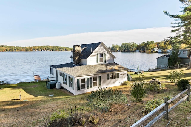 exterior space featuring a lawn, a water view, and fence