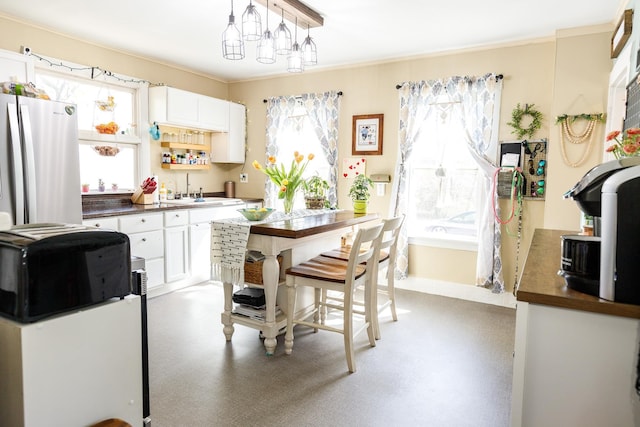 kitchen featuring crown molding, freestanding refrigerator, white cabinets, and dark countertops