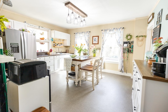 kitchen with white cabinetry, a sink, stainless steel fridge, and ornamental molding