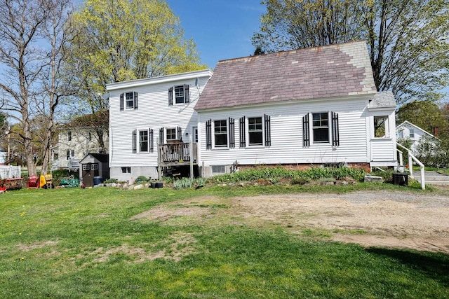 rear view of house featuring a lawn and a shingled roof