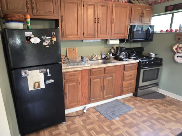 kitchen featuring a sink, brown cabinets, black appliances, light countertops, and baseboards