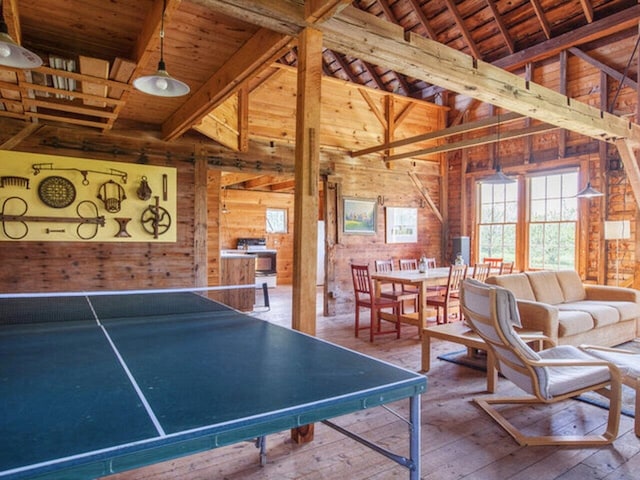 playroom with wooden walls, wooden ceiling, lofted ceiling with beams, and hardwood / wood-style floors