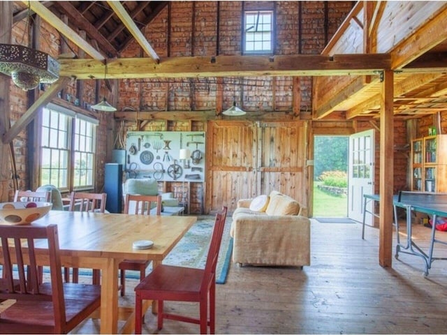 dining space featuring wood-type flooring, wooden walls, high vaulted ceiling, and beamed ceiling