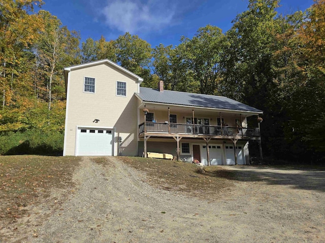 view of front of house featuring an attached garage, driveway, a chimney, and metal roof