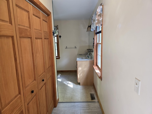 hall with light tile patterned floors, baseboards, and visible vents