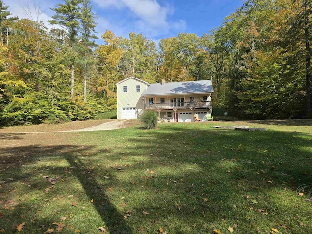 back of house featuring a lawn, a view of trees, a wooden deck, and an attached garage