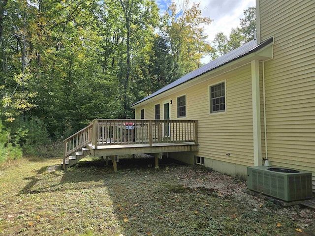 exterior space with central air condition unit, a wooden deck, and metal roof