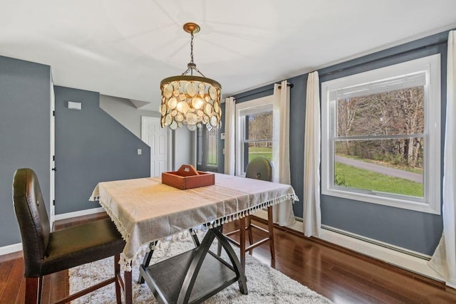 dining space featuring baseboards, dark wood-style flooring, and a notable chandelier