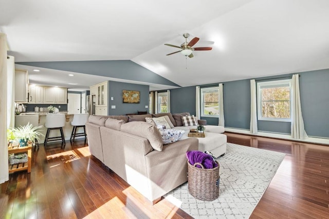 living area with ceiling fan, vaulted ceiling, and dark wood-style floors