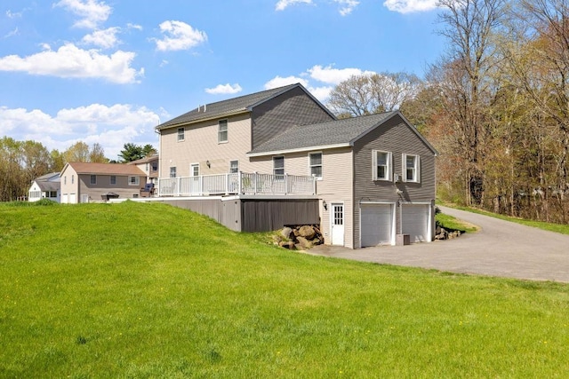 rear view of property featuring a lawn, an attached garage, and aphalt driveway