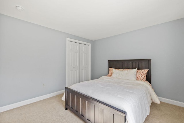 bedroom with light colored carpet, baseboards, and a closet