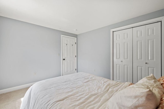 carpeted bedroom featuring baseboards and a closet
