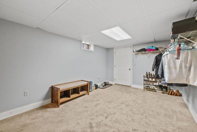 below grade area with carpet floors, baseboards, and a paneled ceiling
