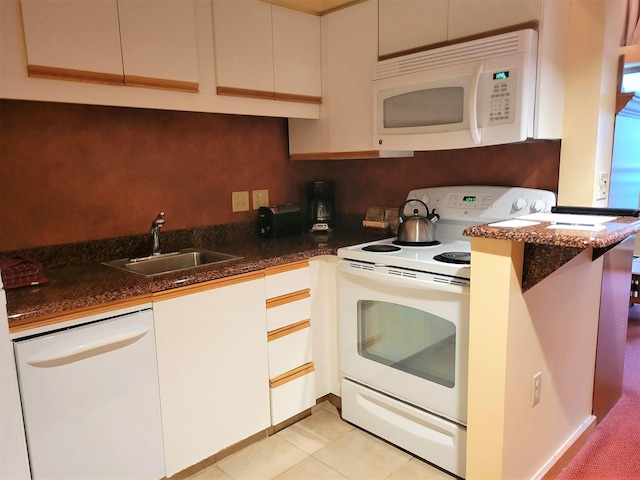 kitchen with a sink, dark stone counters, light tile patterned floors, and white appliances