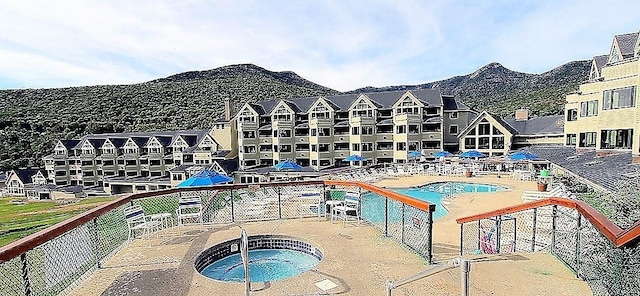 community pool featuring a community hot tub, a patio area, and a mountain view