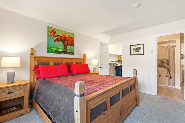 carpeted bedroom featuring baseboards and a walk in closet