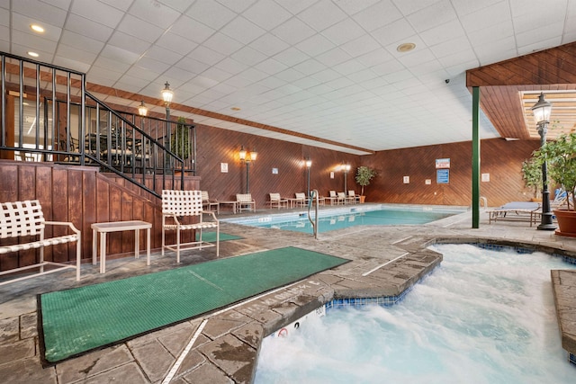 community pool with a patio, an indoor hot tub, and stairway