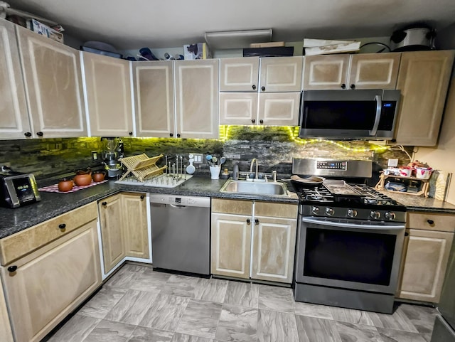 kitchen featuring a sink, appliances with stainless steel finishes, backsplash, and dark countertops