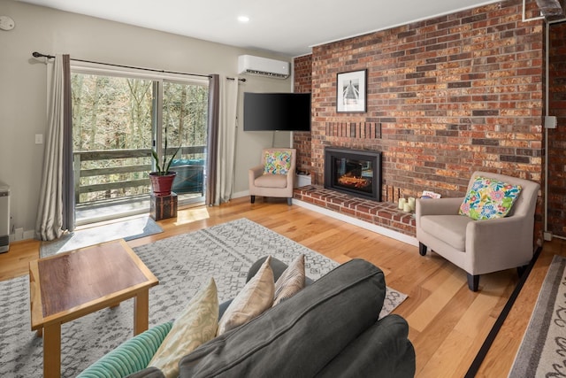 living room with a brick fireplace, recessed lighting, a wall unit AC, and wood finished floors