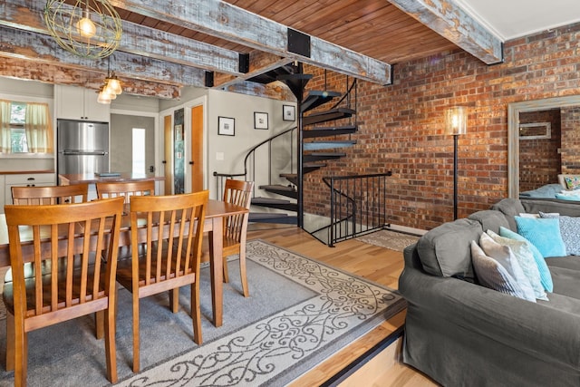 dining room with beam ceiling, wooden ceiling, light wood-style flooring, and brick wall