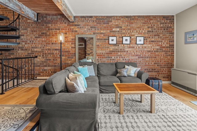 living room with heating unit, baseboards, brick wall, and wood finished floors