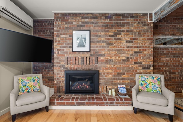 sitting room featuring a fireplace, a wall mounted AC, and wood finished floors