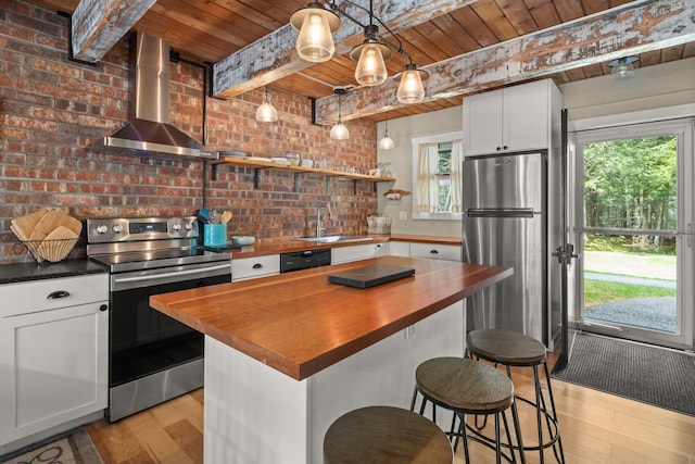 kitchen featuring wall chimney range hood, light wood-style flooring, stainless steel appliances, wood ceiling, and butcher block counters