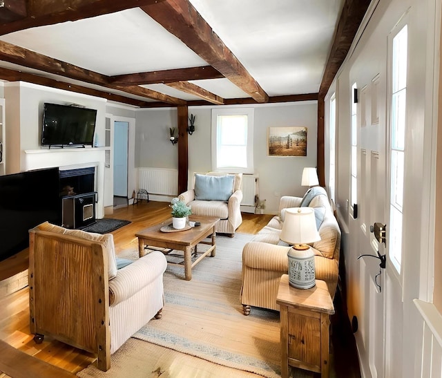 living room featuring wood finished floors, beam ceiling, radiator heating unit, and a wainscoted wall