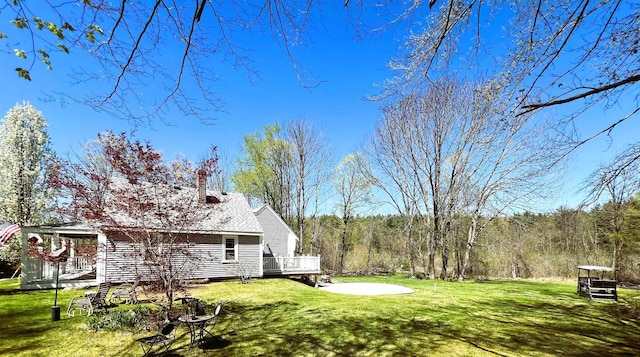 view of yard featuring a view of trees and a wooden deck