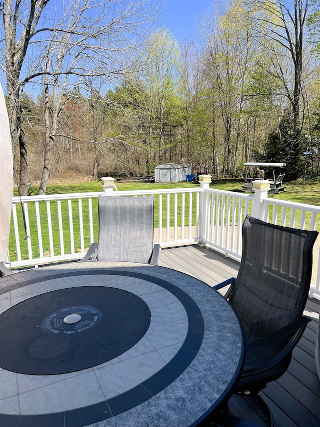 deck featuring a lawn, an outdoor structure, and a storage unit