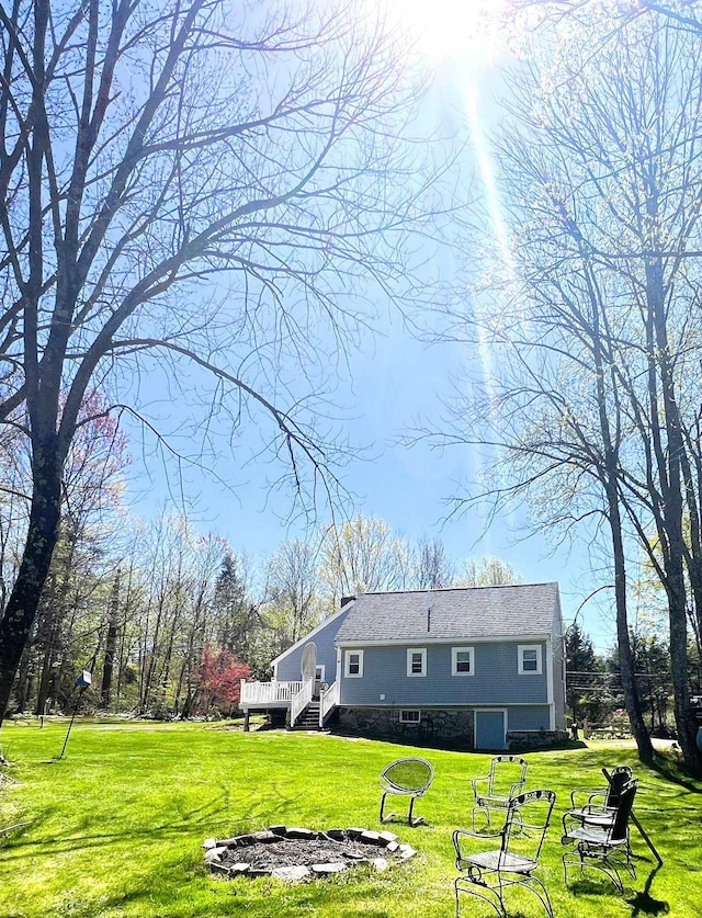 back of property featuring a lawn, a deck, an outdoor fire pit, and stairway