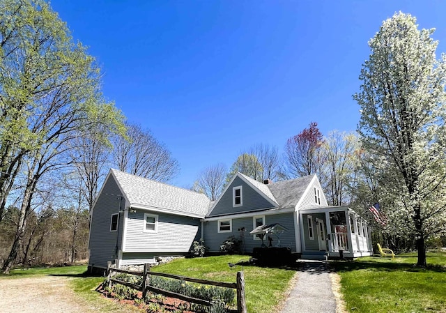 view of front of house with dirt driveway, roof with shingles, fence, and a front yard