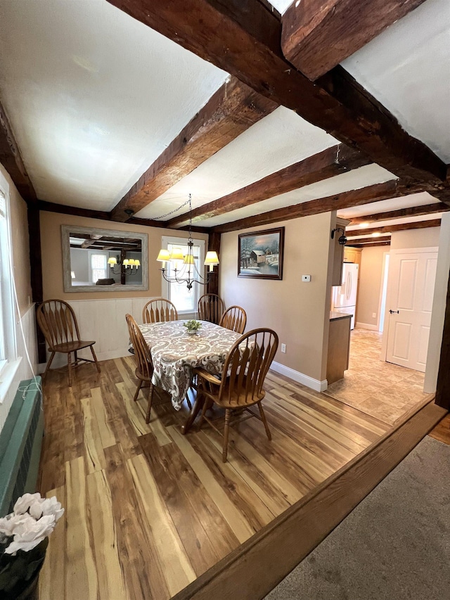 dining room featuring light wood-type flooring, beamed ceiling, baseboards, and an inviting chandelier