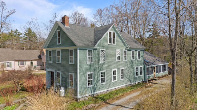 view of side of property featuring roof with shingles and a chimney