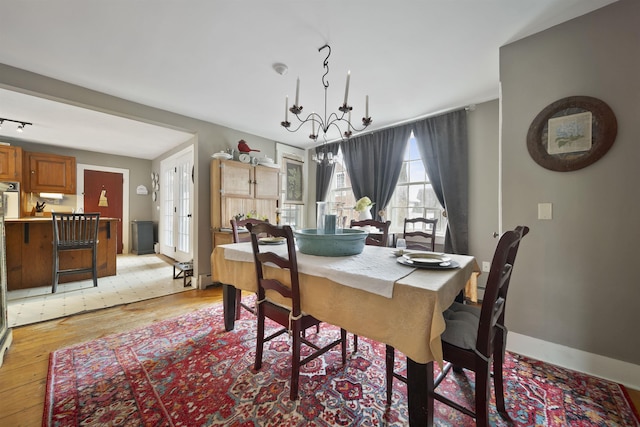 dining room with baseboards, light wood finished floors, and a notable chandelier