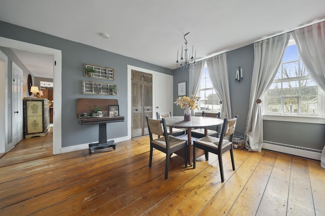 dining area featuring baseboards, a baseboard heating unit, a chandelier, and hardwood / wood-style floors