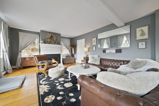 living room featuring a brick fireplace, beamed ceiling, and hardwood / wood-style flooring