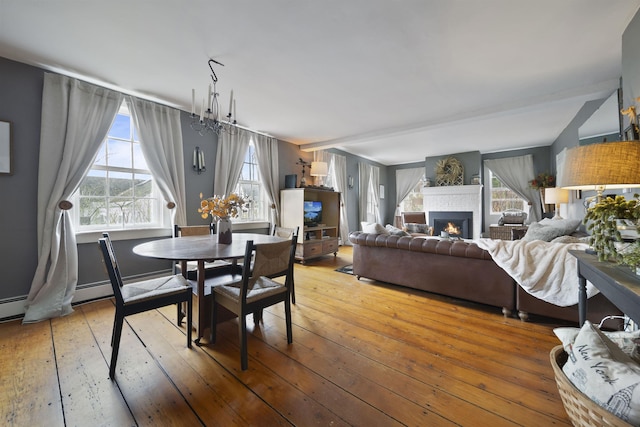 dining space featuring a warm lit fireplace and light wood-style flooring
