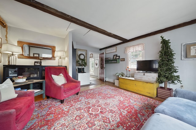 living area with baseboards and beamed ceiling