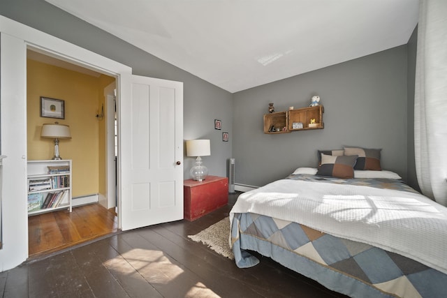 bedroom with vaulted ceiling, baseboard heating, and hardwood / wood-style floors