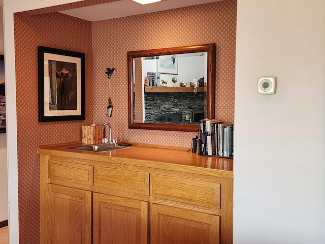 room details featuring baseboards, wallpapered walls, and a sink