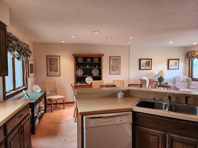 kitchen featuring a sink, dishwasher, light carpet, and light countertops