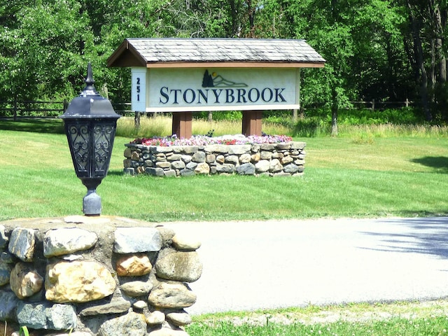 community / neighborhood sign featuring a yard and fence