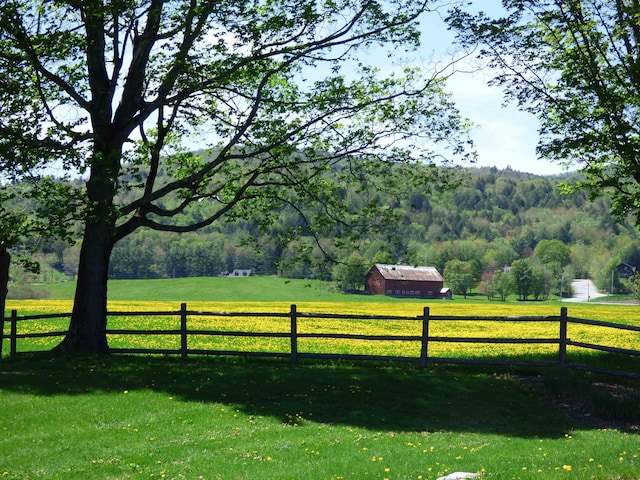 exterior space featuring a wooded view, fence, and a rural view